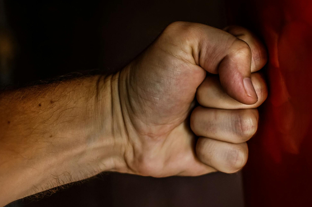 A clenched fist making contact with a surface, symbolizing strength and determination.